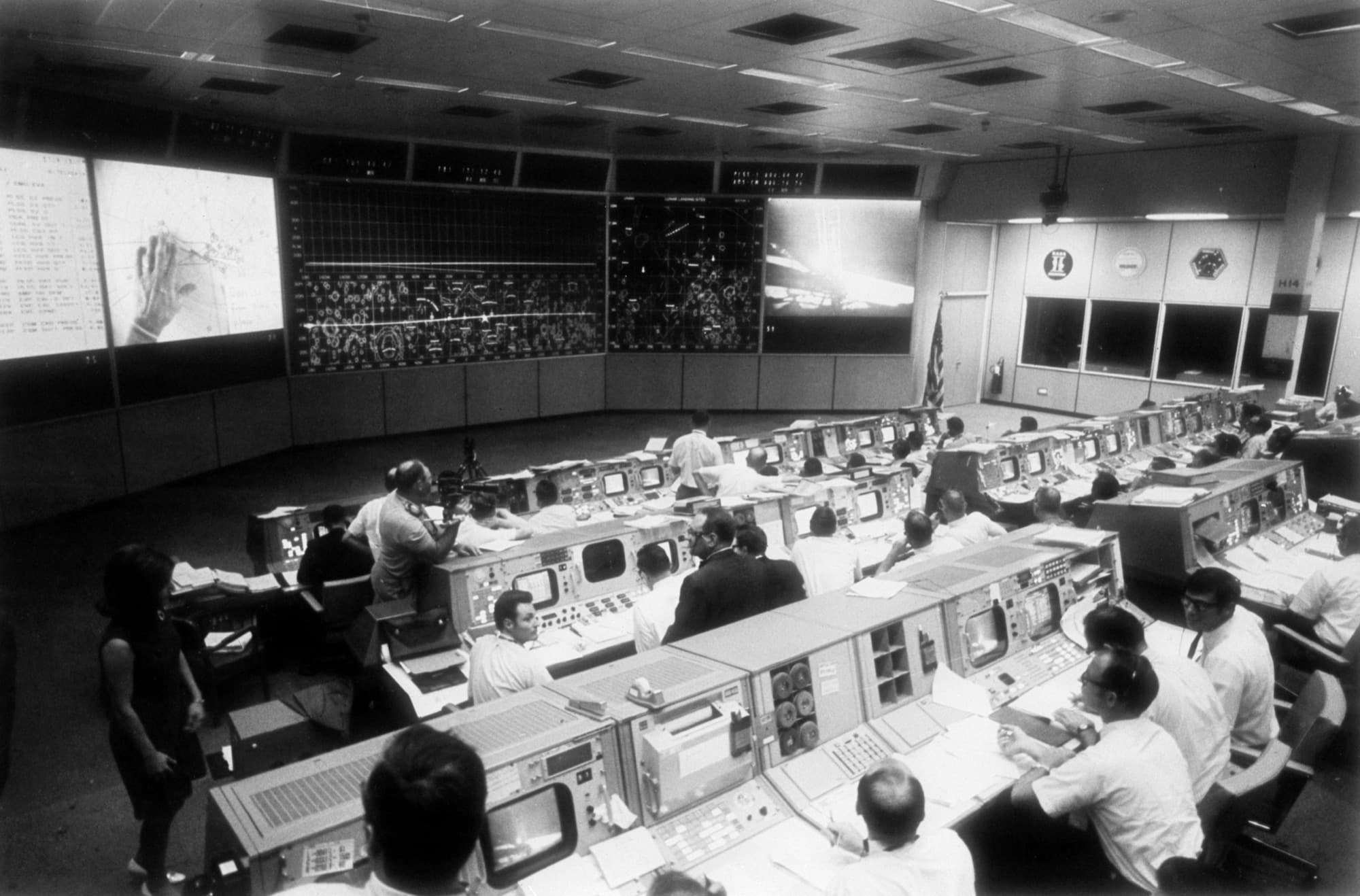 Mission Operations Control Room in Houston during the Apollo 11 moonwalk, rows of consoles facing the big boards